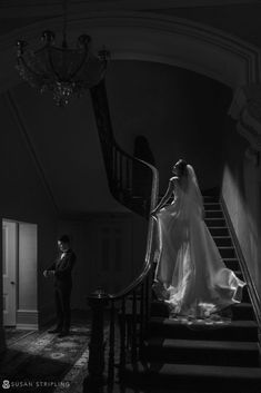 a bride and groom walking down the stairs at their wedding reception in black and white