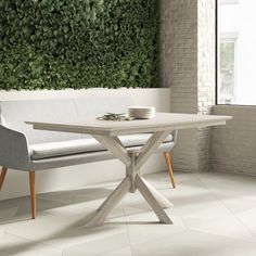 a table with two chairs and a bench in front of a green wall that has plants growing on it