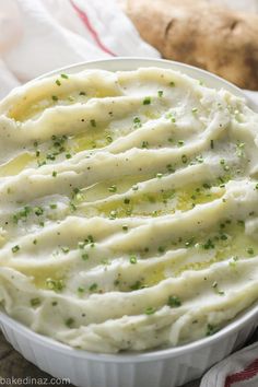 mashed potatoes in a white dish with green sprinkles on the top