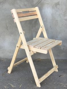 a wooden folding chair sitting in front of a cement wall