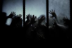 many people are reaching their hands out through the bars