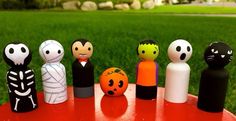 a group of small wooden figures sitting on top of a red table in front of green grass