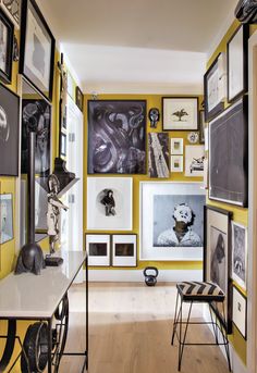 a room with yellow walls and pictures on the wall, along with black and white artwork