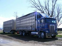 a large blue truck parked on top of a dirt road