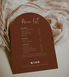 a menu card with the price list on it sitting next to a white cloth and some dry grass