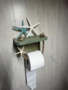 a wooden shelf holding two rolls of toilet paper and starfish on top of it