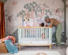 an older man and young child standing in front of a crib with wallpaper