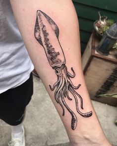 an octopus with a knife tattoo on the left inner forearm and arm, is shown in black ink