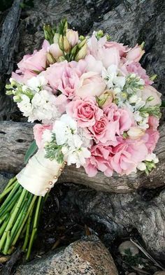 the bridal bouquet is sitting on top of a tree branch with white and pink flowers