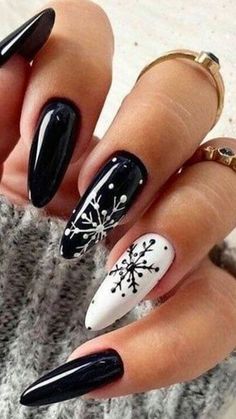 black and white stiled nails with snowflakes on the tip, one nail is