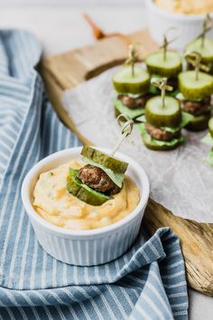 an appetizer is served in a bowl with pickles on the side