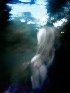 a blurry image of a person standing in the dark with their back turned to the camera