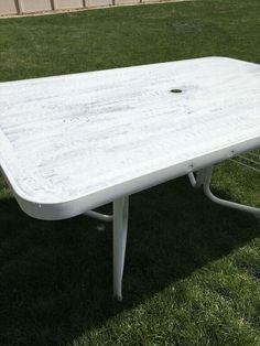 a white table sitting on top of a lush green field