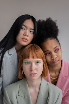 three young women with bright makeup posing for the camera