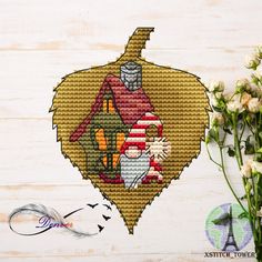 a cross stitch ornament hanging on a wall next to flowers