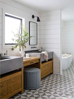 a bathroom with black and white tile flooring and wooden vanity, two sinks and a large mirror