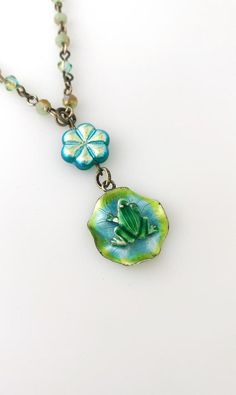 This sweet necklace is made using a vintage enamel frog on lily pad sterling silver pendant, a glass flower bead, and a crystal beaded necklace.  The necklace is 16 inches long, with a 1 1/2 inch drop.It is handmade and a one of a kind! Adjustable Green Enamel Jewelry, Unique Turquoise Czech Glass Jewelry, Whimsical Green Nickel-free Jewelry, Whimsical Blue Jewelry With Flower Charm, Nickel-free Green Flower Pendant Jewelry, Unique Jewelry With Flower Charm, Whimsical Czech Glass Silver Jewelry, Vintage Turquoise Enamel Jewelry, Whimsical Silver Czech Glass Jewelry