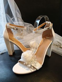 a pair of white shoes with flowers on the heel and veil hanging from the back