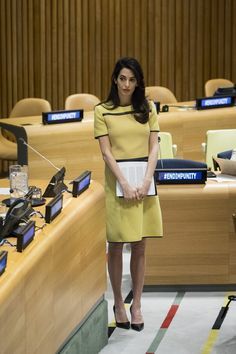 a woman in a yellow dress standing next to a table full of computers and monitors