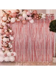 a pink and white backdrop with balloons, flowers and streamers on the wall in front of it