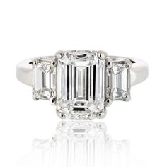 an emerald cut diamond ring with three baguets on the shoulders and side stones