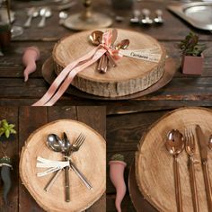 there are forks, spoons and knives on the wooden plate holders that have ribbons tied around them