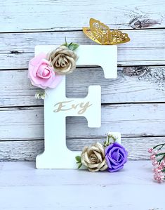 the letter e is decorated with flowers and gold foil lettering that says,'joy '