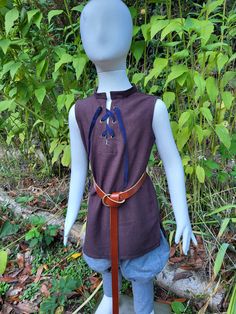 This tunic is made of soft linen in dark chocolate brown. It is a medieval or renaissance style, would be great for ren faires, SCA, pirate costumes, pioneer events, etc. Cool and comfortable, and machine washable and dryable, it makes an ideal piece for a kid's costume. It is a loose fitting pullover with metal grommets and cotton ribbon lacing at the neck and has a short standing collar, and is a bit longer than a normal shirt. Although it is perfect for hot weather, it looks great as a layer with another shirt or tunic under it for cooler weather.  (This listing is for the sleeveless tunic only, but pants, belt, shirt, and shoes can be found in our shop as well) Kids can vary in size a lot, so please see measurement chart below for best fit: ChestLength 12-18 m....18"-20"17" 2T20"-22"17 Medieval Tunic, Pirate Costumes, Belt Shirt, Coos Bay, Cotton Ribbon, Dark Chocolate Brown, Standing Collar, Pirate Costume, Sleeveless Tunic