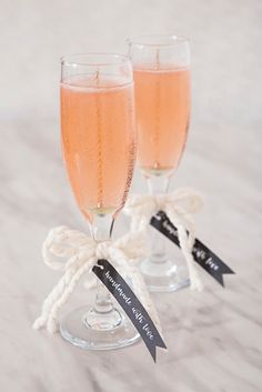 two champagne flutes with labels on them sitting next to each other