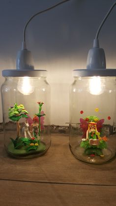 two glass jars with fairy figurines in them