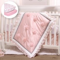 a baby crib bedding set with pink and white flowers on the coverlet