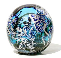 a glass ball with blue and white designs on the outside, sitting in front of a white background