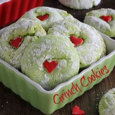 some heart shaped cookies in a green bowl on a table with red hearts around them