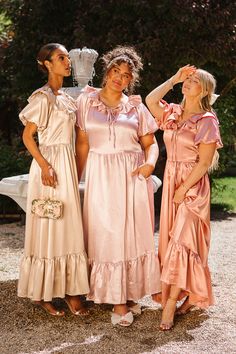 three women standing next to each other in dresses