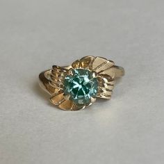 Art Nouveau 10K Blue Topaz Ring, Size 6.25, 3.4 grams- absolutely stunning Size: 6.25 Weight: 3.4 grams Stone: Blue Topaz Color: Green-Blue Size Stone: ca. 7.25mm dia. Cut: Round Marking: 10K (inside Band) Band Material: 10K Solid Yellow Gold and White Gold Bandwidth: xxmm at smallest point Tested: Machine Tested with Thermo Fisher Scientific Niton DXL Precious Metals Analyzer Condition: Good preowned- wear out throughout -refer to pictures for condition. Ring has signs of prior sizing adjustmen Green Round Topaz Ring For Anniversary, Green Topaz Ring For Anniversary, Green Round Cut Topaz Ring For Anniversary, Collectible Heirloom Solitaire Ring, Vintage Diamond Ring With Center Stone For May Birthstone, Vintage 14k Gold Emerald Ring With Center Stone, Formal Fine Jewelry Topaz Ring For May Birthstone, Vintage Concave Jewelry For Anniversary, Formal May Birthstone Topaz Ring