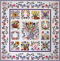 a white quilt with flowers and birds on it's border, in the shape of a square