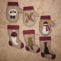 four stockings with snowmen and christmas trees hanging from them on the floor in front of a wall