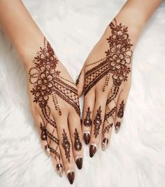 two hands with hendi designs on them, one is brown and the other is white