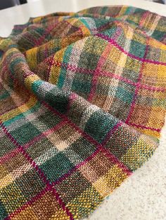 a multicolored blanket sitting on top of a counter next to a white table