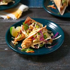 two plates with tacos on them sitting on a table next to other plates and utensils