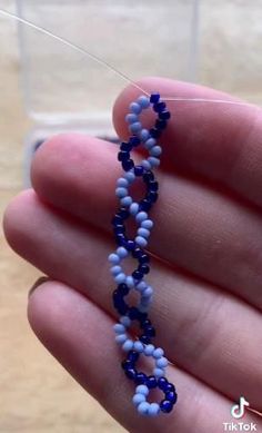 a hand holding a blue and white beaded necklace in it's left hand