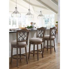 three bar stools in front of an island with lights hanging from the ceiling over it