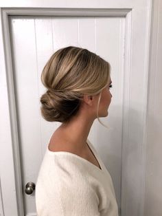 a woman standing in front of a white door with her hair pulled into a low bun