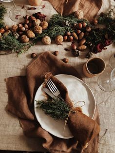 a white plate topped with a fork next to a napkin covered in nuts and greenery