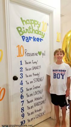 a young boy standing in front of a birthday sign