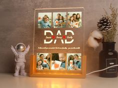 an illuminated photo frame with the words dad on it next to a small toy and a pine cone