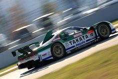 a race car driving on a track with motion blurry in the background and grass