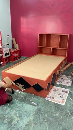 a woman laying on the ground next to a cardboard bed with open shelves above it