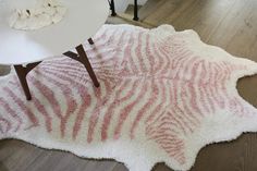 a white table sitting on top of a wooden floor next to a zebra print rug