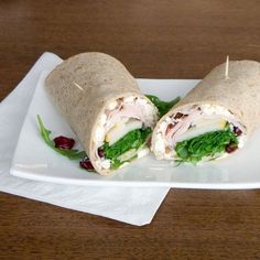 a wrap with meat, lettuce and cheese on it sitting on a plate